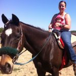 Fallon Nunes, a member of the US Army military police, combat support, sits with her 22-month-old daughter on Mercuriandarkside, her heart horse.